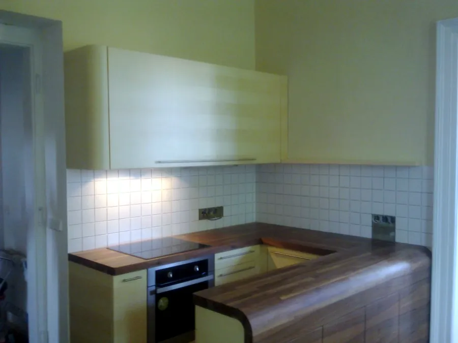 Rohová kuchyňská linka se světlými dvířky a tmavou deskou